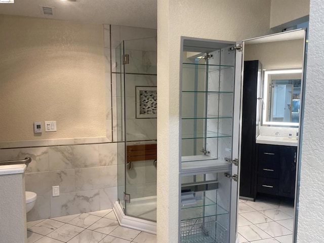 bathroom with toilet, vanity, tile walls, and walk in shower