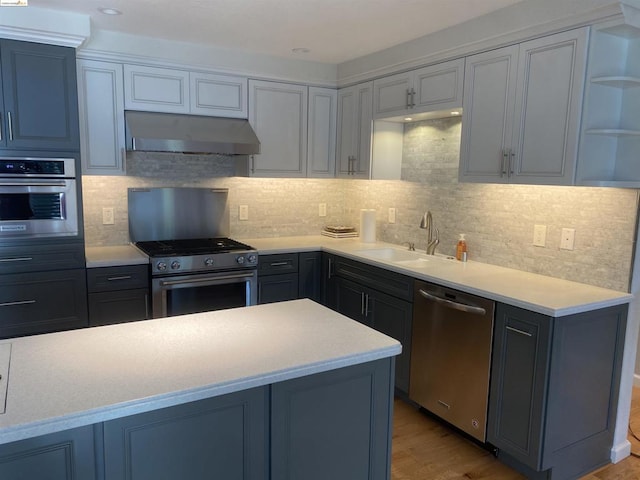 kitchen with decorative backsplash, stainless steel appliances, light hardwood / wood-style flooring, and sink