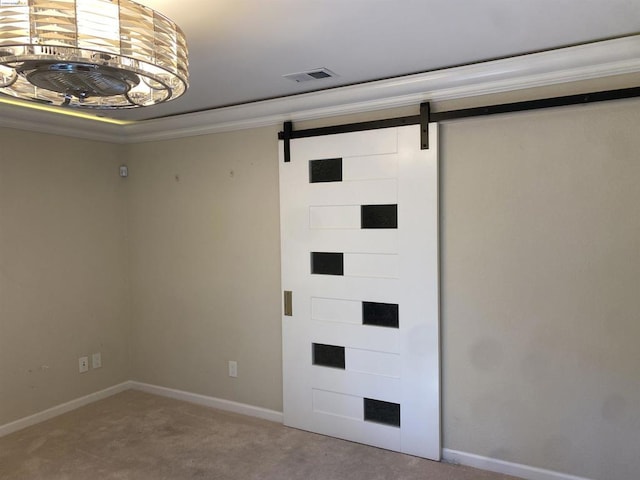 interior space with a barn door, carpet, and ornamental molding