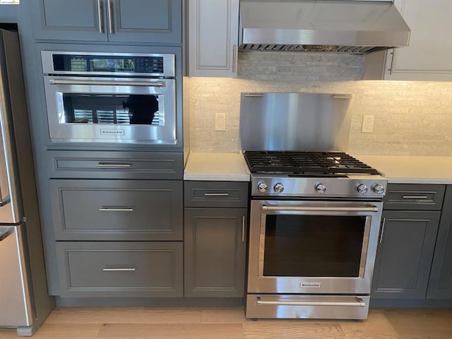 kitchen with backsplash, wall chimney range hood, and stainless steel appliances