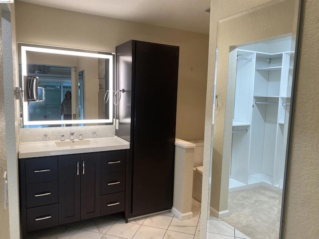 bathroom with a textured ceiling, vanity, tile patterned floors, and backsplash