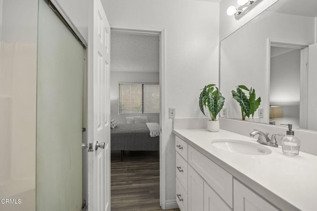 bathroom with hardwood / wood-style flooring, a shower with shower door, and vanity