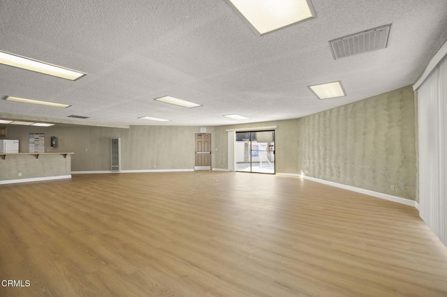 empty room with a textured ceiling and light hardwood / wood-style floors