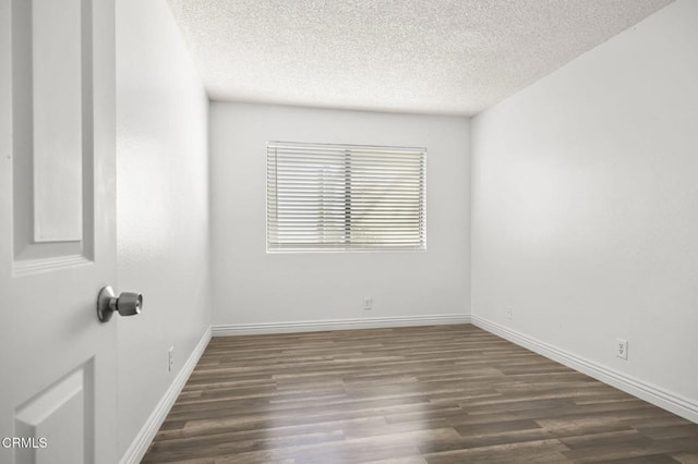 empty room featuring dark hardwood / wood-style flooring and a textured ceiling