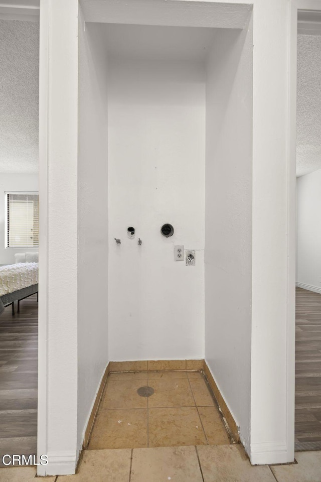 laundry room featuring washer hookup, a textured ceiling, tile patterned floors, and hookup for an electric dryer