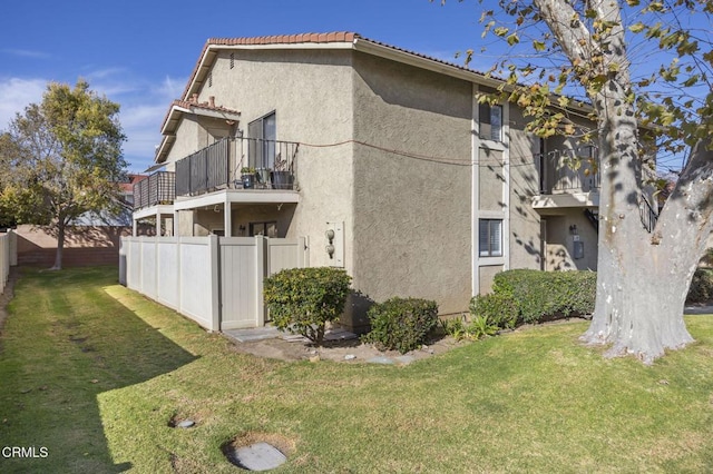 back of property with a lawn and a balcony