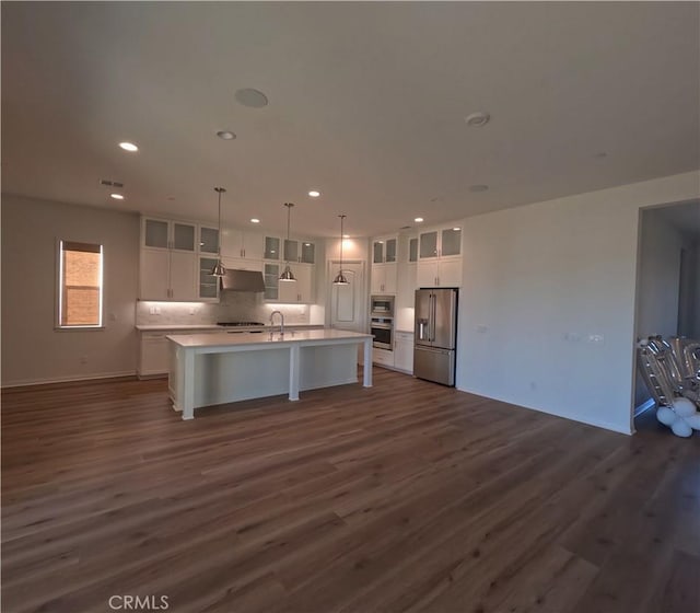 kitchen featuring a center island with sink, high quality fridge, decorative light fixtures, dark hardwood / wood-style flooring, and white cabinetry