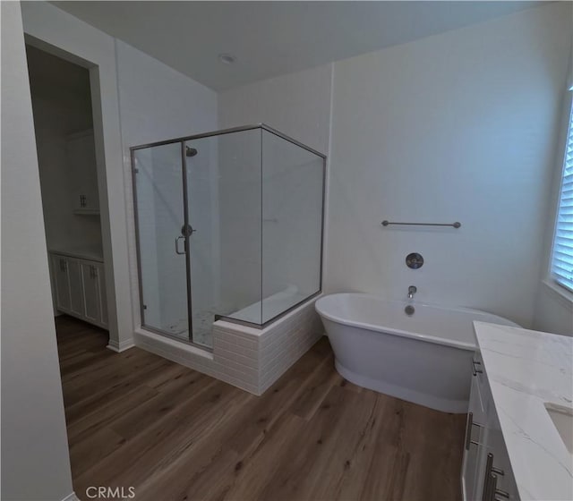 bathroom with plus walk in shower, wood-type flooring, and vanity