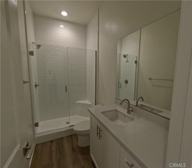 bathroom featuring wood-type flooring, vanity, toilet, and walk in shower