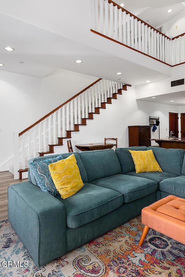 living room with a towering ceiling, hardwood / wood-style flooring, and sink