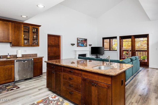 kitchen with sink, an island with sink, stainless steel dishwasher, and light hardwood / wood-style floors