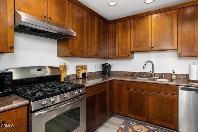 kitchen featuring dark stone countertops, sink, stainless steel appliances, and light wood-type flooring