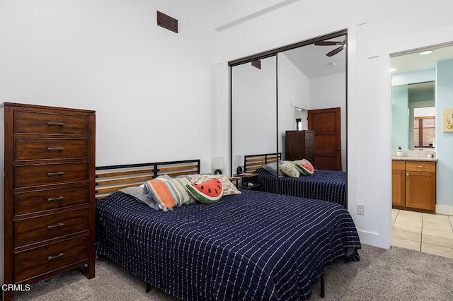 bedroom featuring a closet, light colored carpet, and ensuite bath