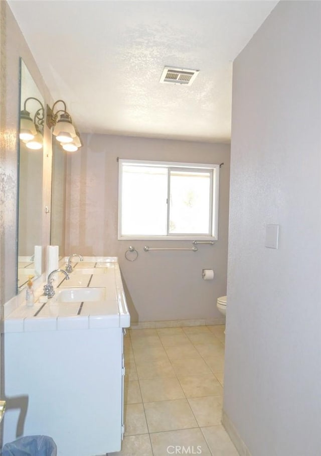 bathroom with vanity, toilet, tile patterned flooring, and a textured ceiling