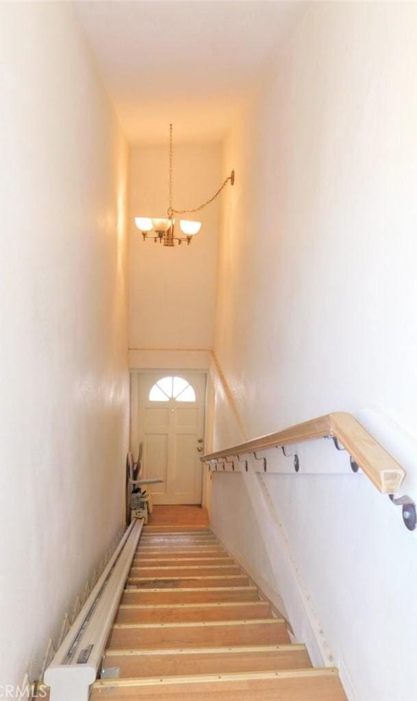 staircase with a chandelier and hardwood / wood-style floors