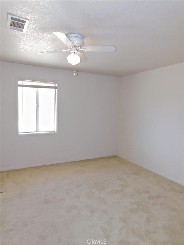 spare room with light carpet, ceiling fan, and a textured ceiling