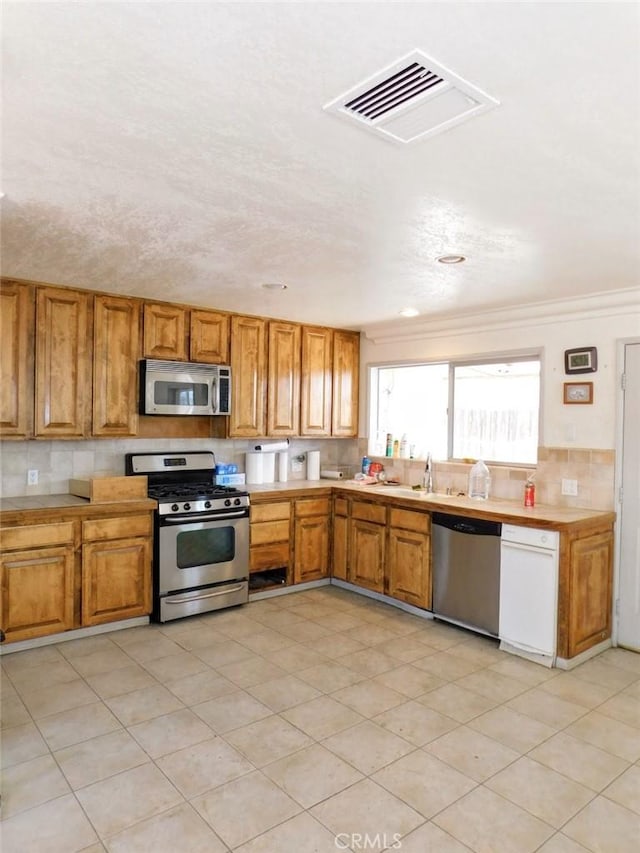 kitchen featuring stainless steel appliances, crown molding, sink, and backsplash