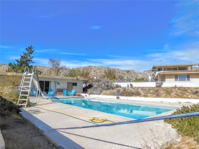 view of swimming pool with a patio, a mountain view, and a water slide