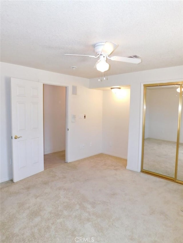 unfurnished room with ceiling fan, light carpet, and a textured ceiling