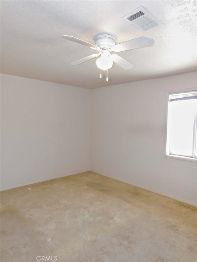 carpeted spare room featuring ceiling fan and a textured ceiling