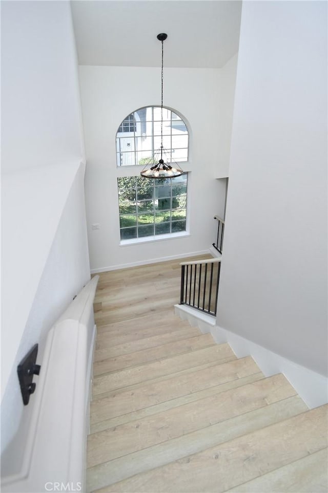 stairway featuring hardwood / wood-style floors and a notable chandelier