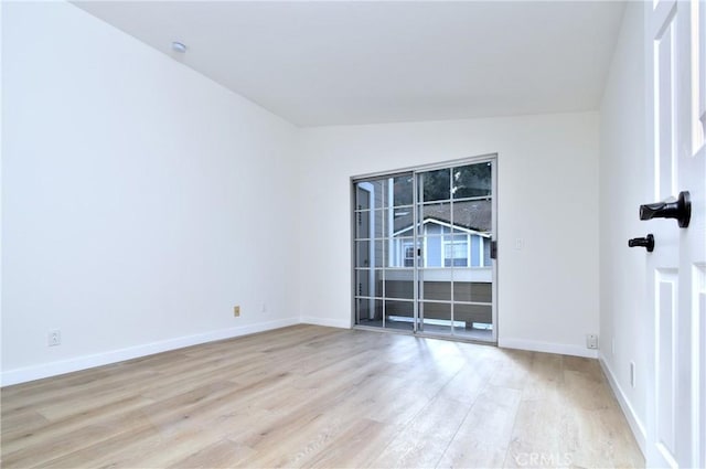 empty room featuring light hardwood / wood-style floors and vaulted ceiling