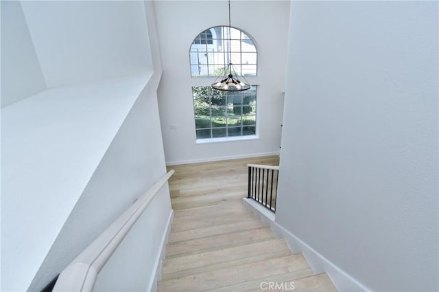 stairs with hardwood / wood-style floors and a chandelier