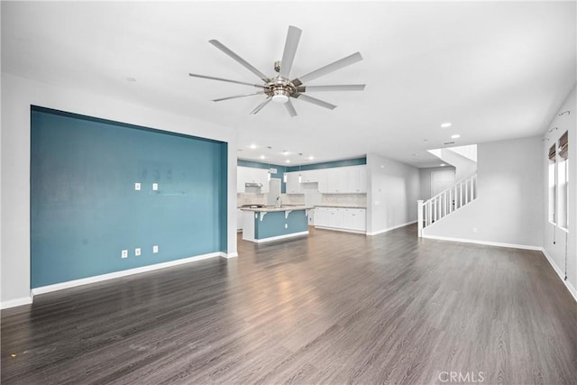 unfurnished living room featuring ceiling fan and dark wood-type flooring