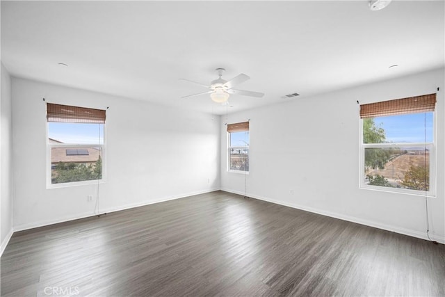 spare room with plenty of natural light, ceiling fan, and dark hardwood / wood-style flooring