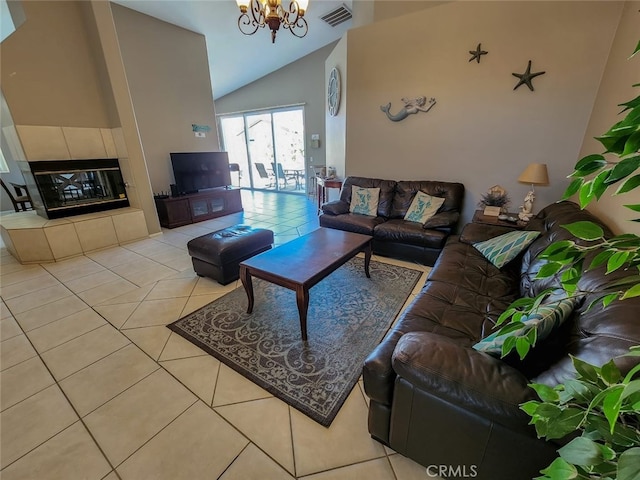 living room featuring a notable chandelier, light tile patterned floors, high vaulted ceiling, and a tiled fireplace