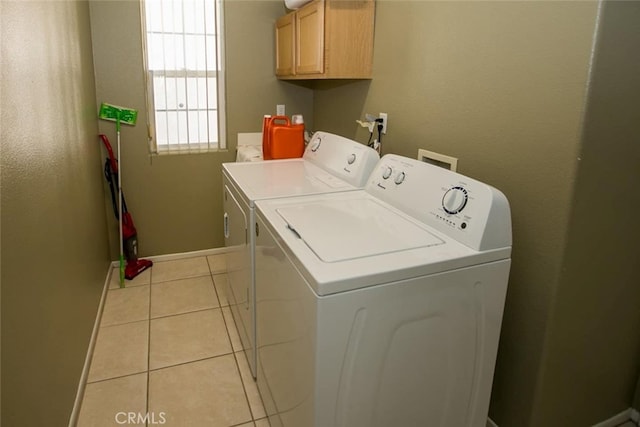 washroom with washer and clothes dryer, light tile patterned floors, and cabinets