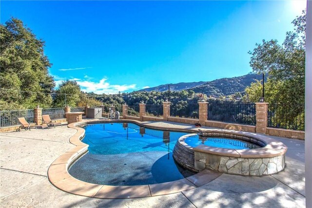 view of pool featuring an in ground hot tub, a mountain view, and a patio