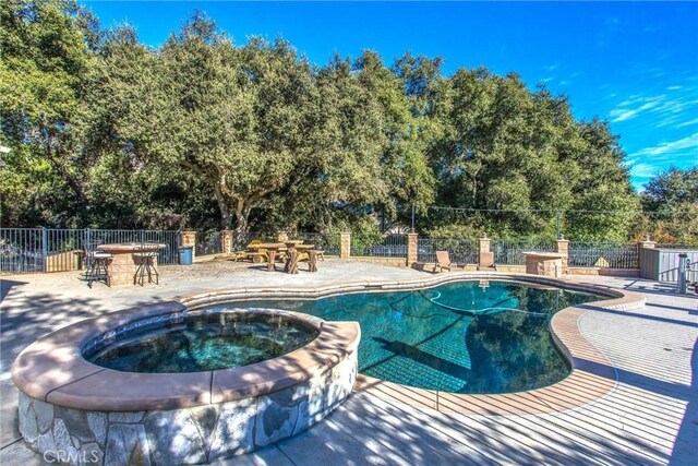 view of pool with a patio area and an in ground hot tub