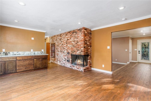 unfurnished living room featuring crown molding, a fireplace, and light wood-type flooring