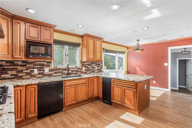 kitchen featuring sink, light stone counters, black appliances, decorative backsplash, and kitchen peninsula