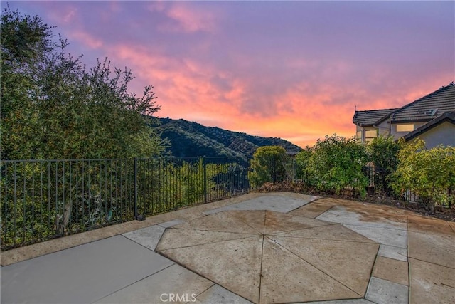 patio terrace at dusk featuring fence and a mountain view