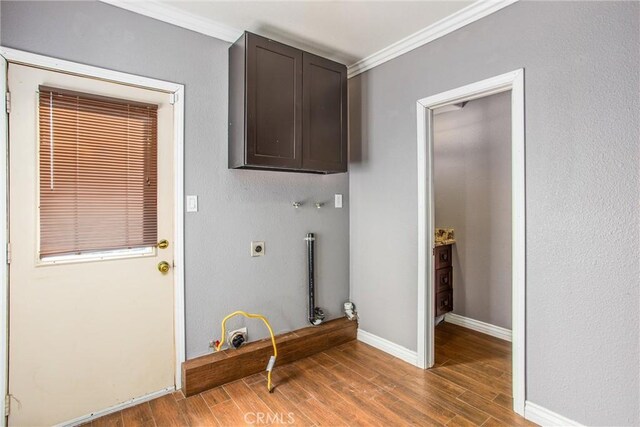 laundry room with gas dryer hookup, electric dryer hookup, cabinets, wood-type flooring, and ornamental molding