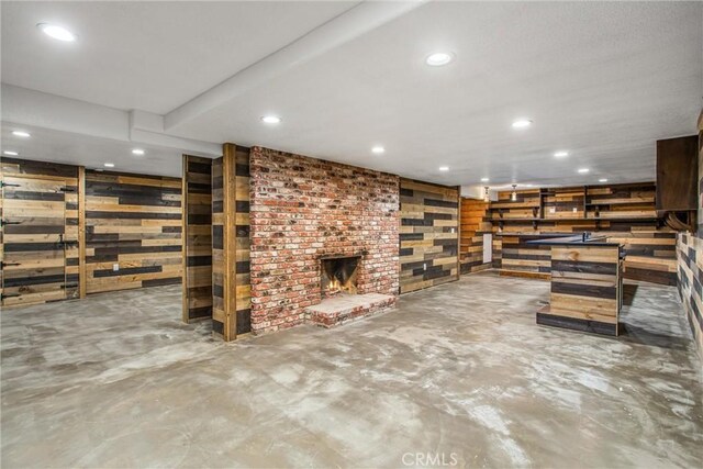 basement featuring a brick fireplace and wooden walls