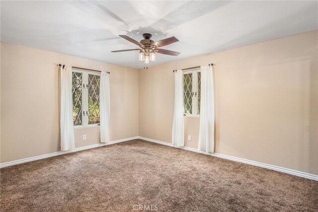 unfurnished room featuring a ceiling fan, carpet, and baseboards