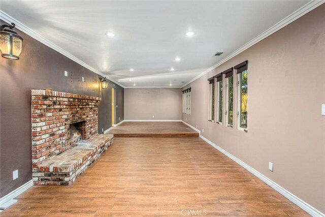 unfurnished living room with crown molding, a fireplace, and light wood-type flooring