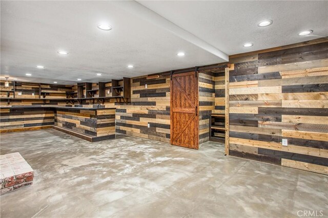 bar with concrete flooring, a barn door, and wooden walls