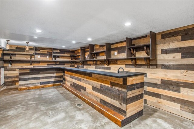 bar with wood walls, concrete flooring, and recessed lighting