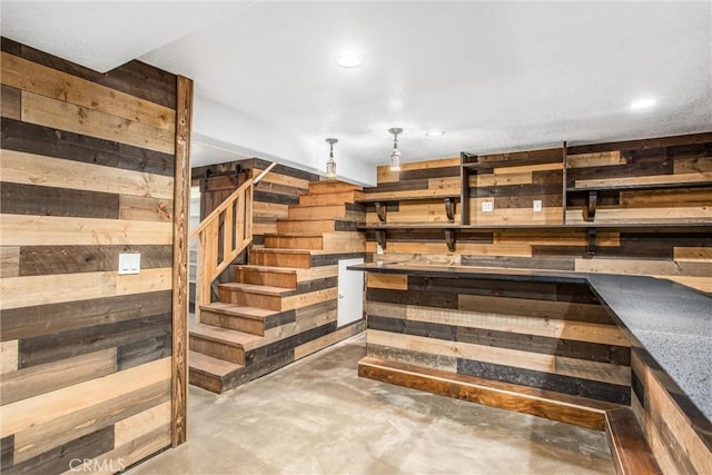 stairs featuring concrete floors and wooden walls