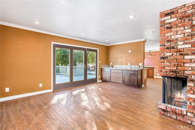 unfurnished living room with crown molding, french doors, a brick fireplace, and light hardwood / wood-style flooring