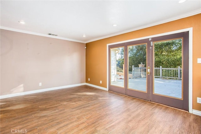 unfurnished room with baseboards, light wood finished floors, visible vents, and crown molding