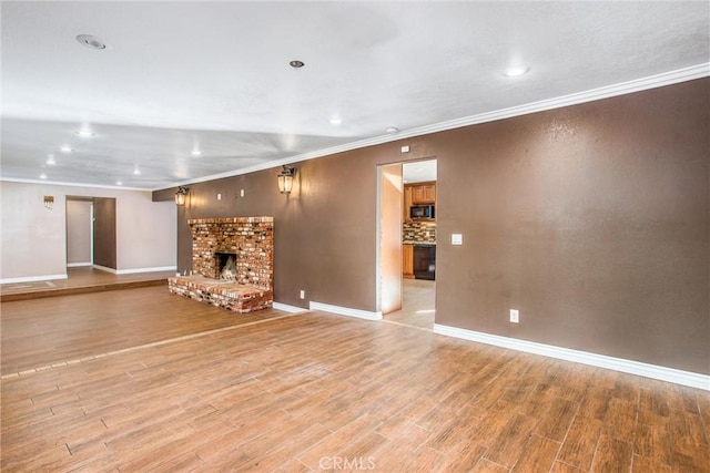 unfurnished living room with ornamental molding, baseboards, a fireplace, and light wood finished floors