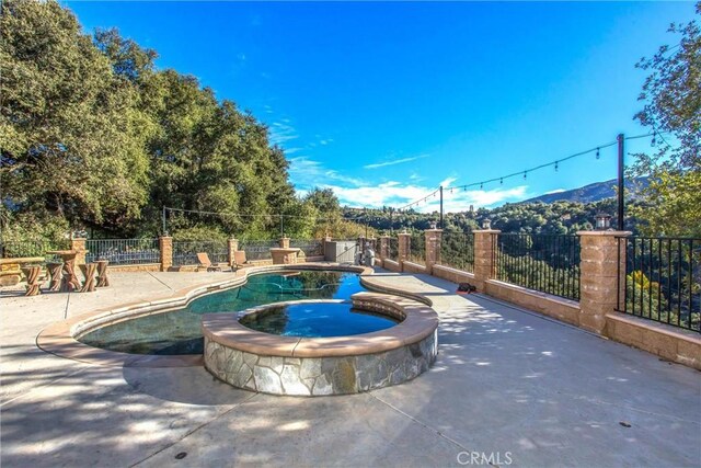 view of swimming pool with an in ground hot tub, a mountain view, and a patio