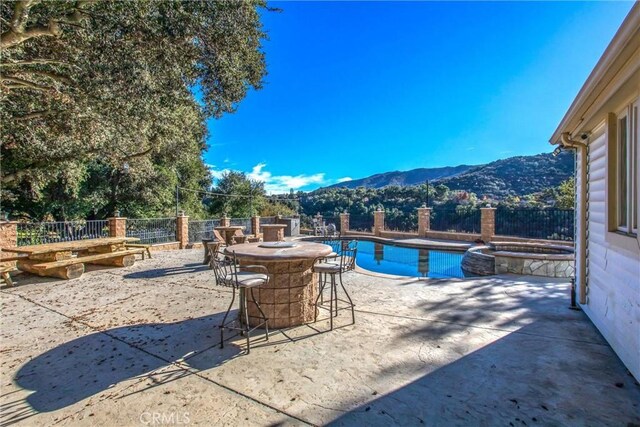 view of swimming pool featuring a mountain view, a patio area, and an in ground hot tub