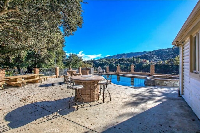 view of swimming pool featuring a pool with connected hot tub, a patio area, a fenced backyard, and a mountain view