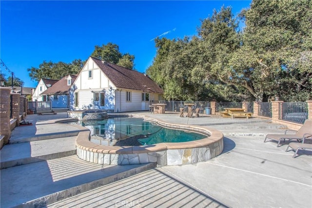 view of pool featuring a pool with connected hot tub, a patio area, and fence